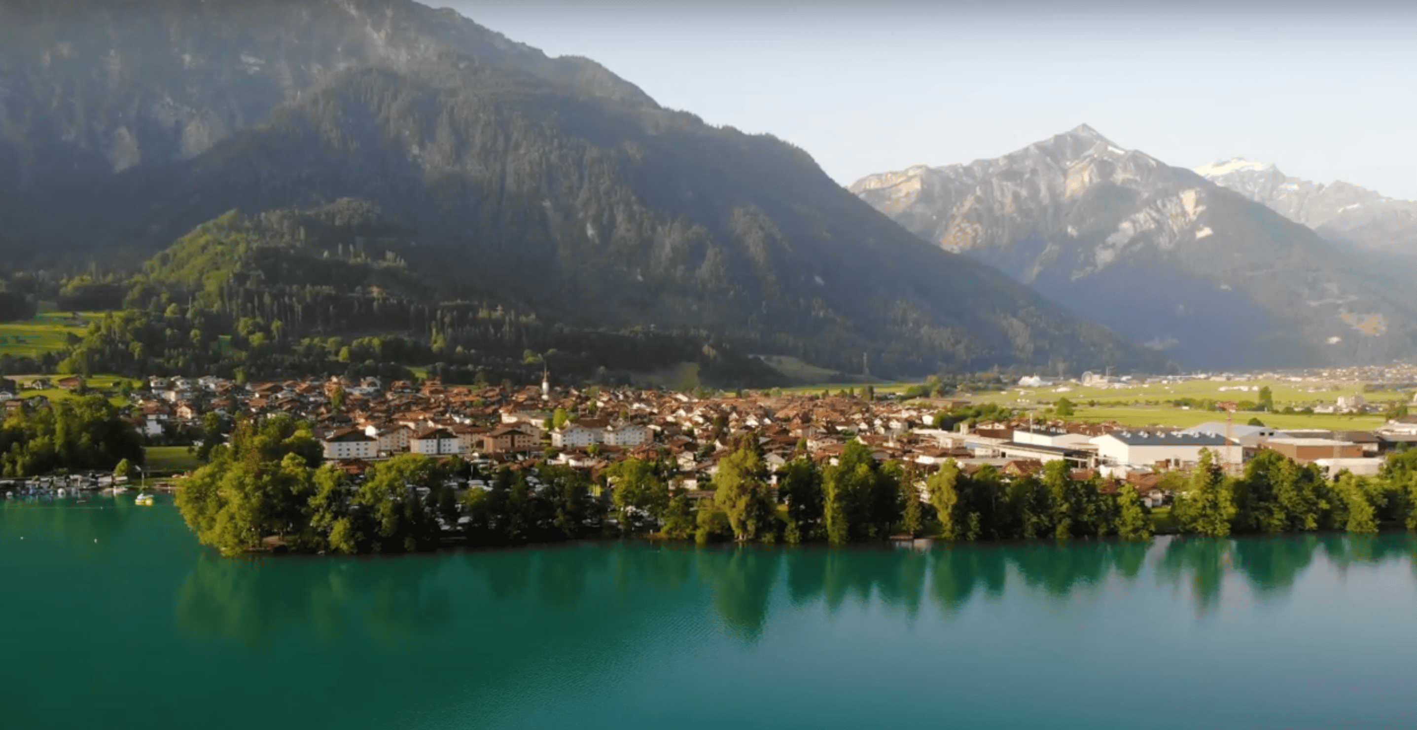 An aerial shot over Interlaken from the lake. The town is right near the water with beautiful mountains cascading in the background.